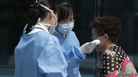 Nhân viên y tế kiểm tra nhiệt độ của một người khách tại Seoul.
